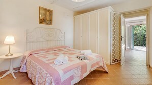Ein Schlafzimmer mit Bett, Nachttisch, Kleiderschrank und einer Tür zu einem Außenbereich.