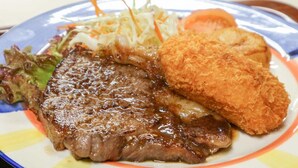 Um prato com bife, acompanhamento empanado e uma salada.