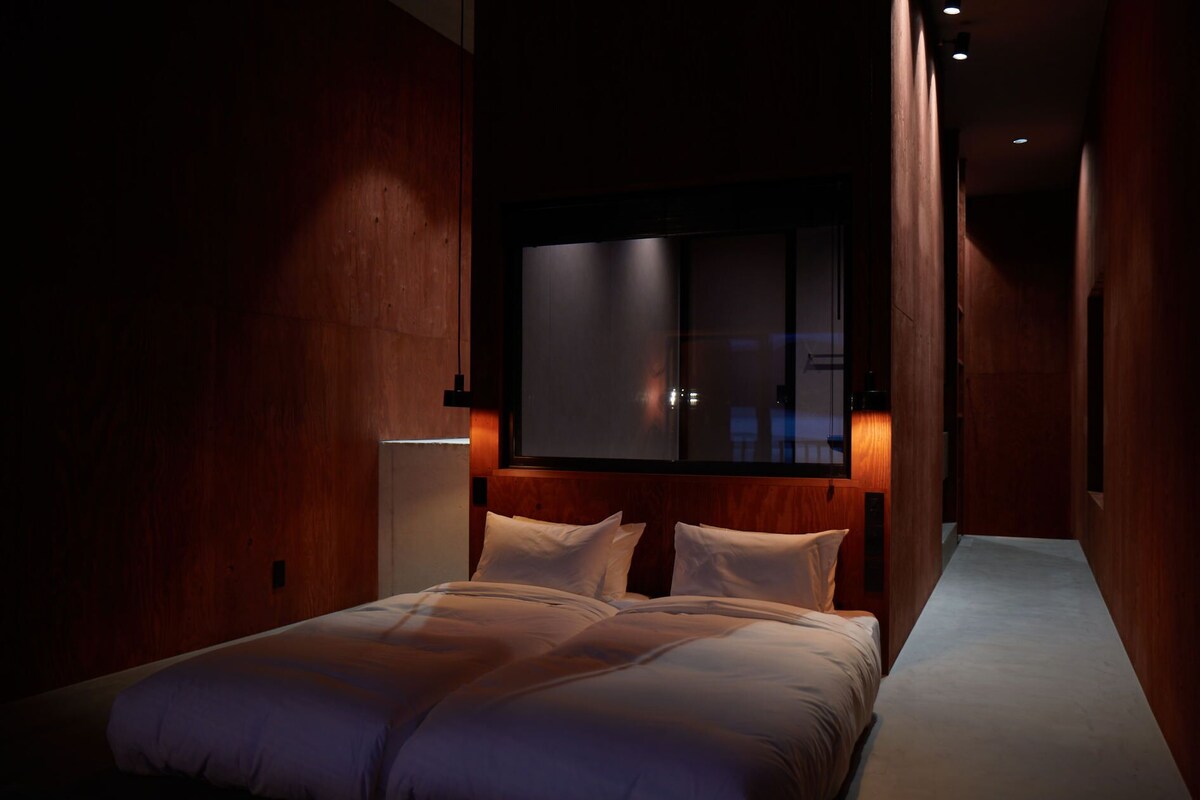 Une chambre à coucher avec un grand lit, des murs en bois et une fenêtre.