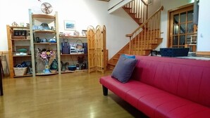 Un salon avec un canapé rouge, des étagères en bois, un escalier et un plancher en bois.