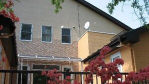 Un bâtiment à deux étages avec une façade en briques, une antenne parabolique et une entrée fermée par un portail.
