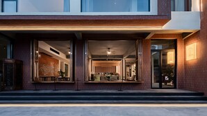 A modern building with large windows, a brick facade, and a visible interior with furniture.