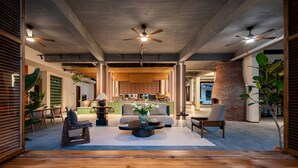 A spacious interior with a central seating area, ceiling fans, and a kitchen in the background.