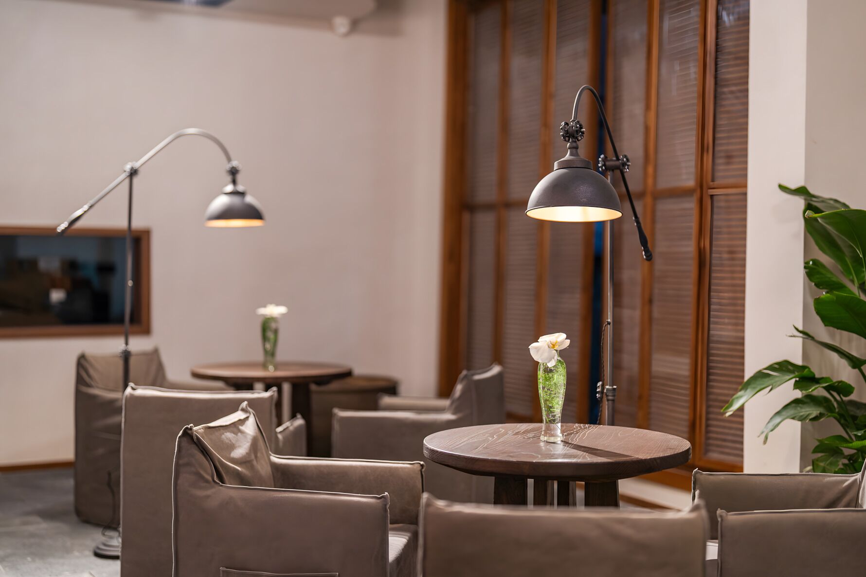 Un intérieur moderne avec des tables rondes, des fauteuils en cuir et des luminaires suspendus.