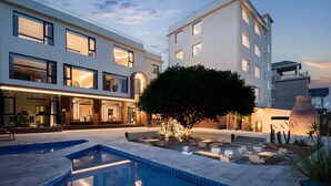 A modern hotel with a pool, outdoor seating, and a large tree in the courtyard.