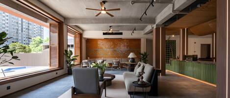 A spacious living area with a high ceiling, large windows, and a view of the cityscape.