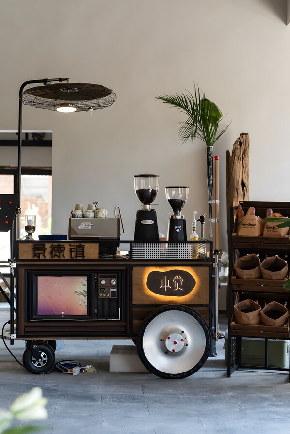 Un chariot à café au design rétro, équipé d’un moulin à café, d’un broyeur et d’un petit écran.
