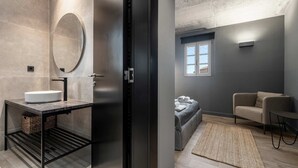 Un baño moderno con lavamanos, espejo y puerta de marco negro.