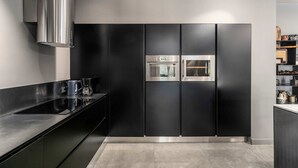 Una cocina moderna con armarios negros, electrodomésticos de acero inoxidable y una encimera elegante.