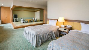 A hotel room with two beds, a bedside table with a lamp, a small table with chairs, and a large mirror. - Hotel de Marronnier Gero Onsen (Gero)