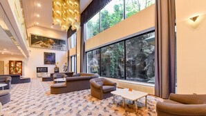 A spacious living area with a large window, comfortable seating, and a decorative chandelier. - Hotel de Marronnier Gero Onsen (Gero)