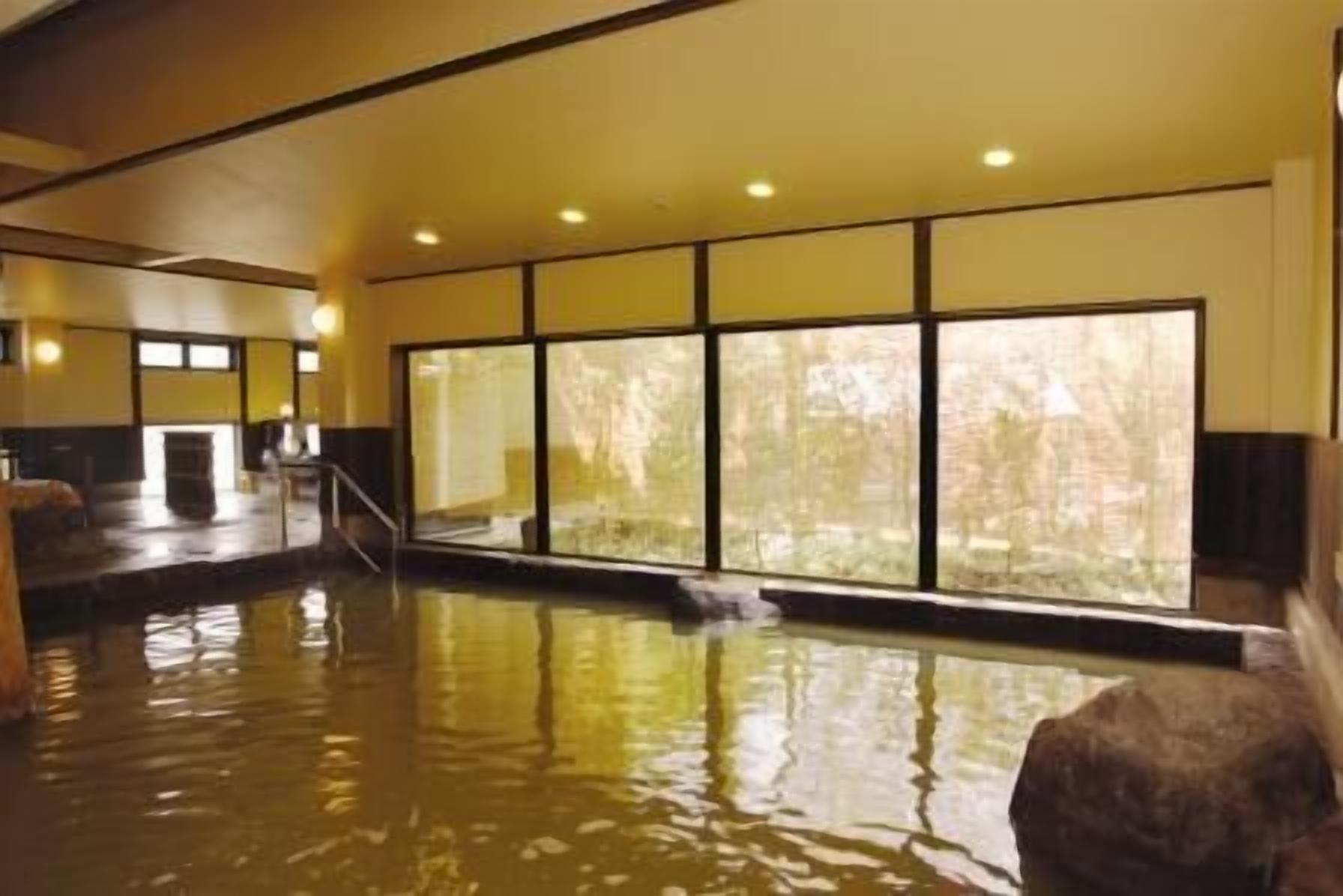 A large indoor pool with clear windows, a stone bench, and a visible exit.