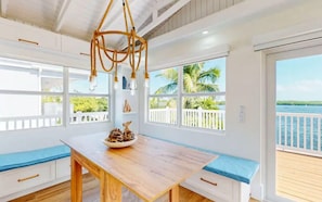 A kitchen with a wooden table, white cabinets, and a view of the ocean. - Luxury Oceanfront Estate | Private Dock • Pool (Key Largo)