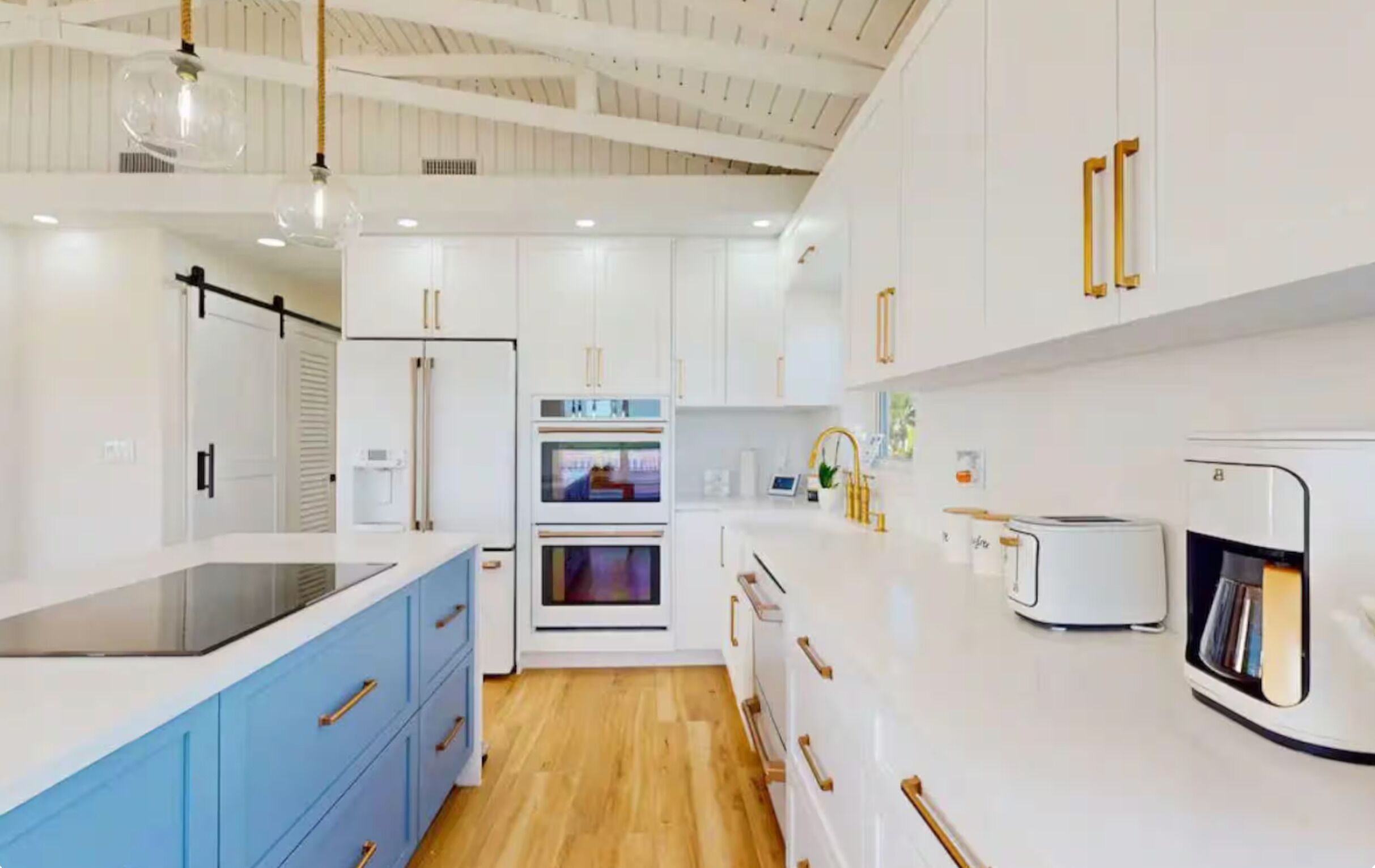 A modern kitchen with white cabinetry, a blue countertop, and a wooden floor.