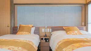Habitació d'hotel amb dos llits, una tauleta de nit amb una làmpada i una finestra amb vistes.