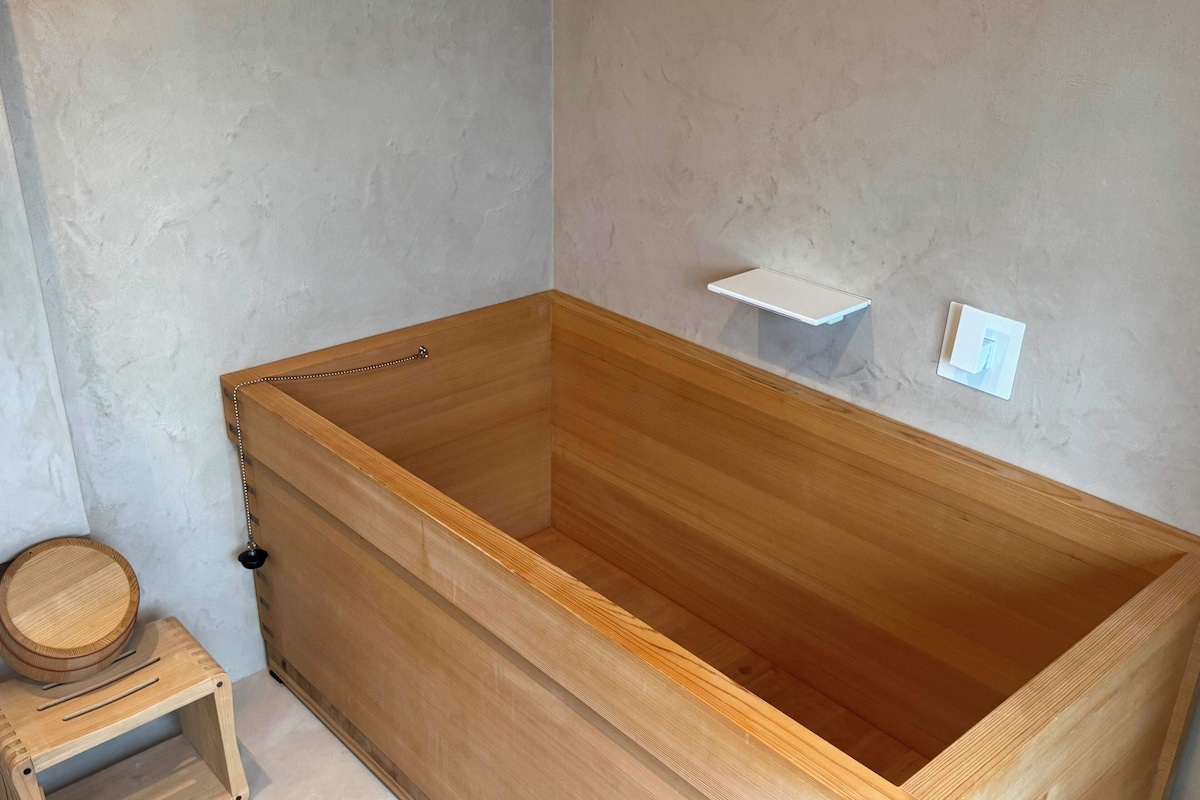 A wooden bathtub with a wooden stool beside it.