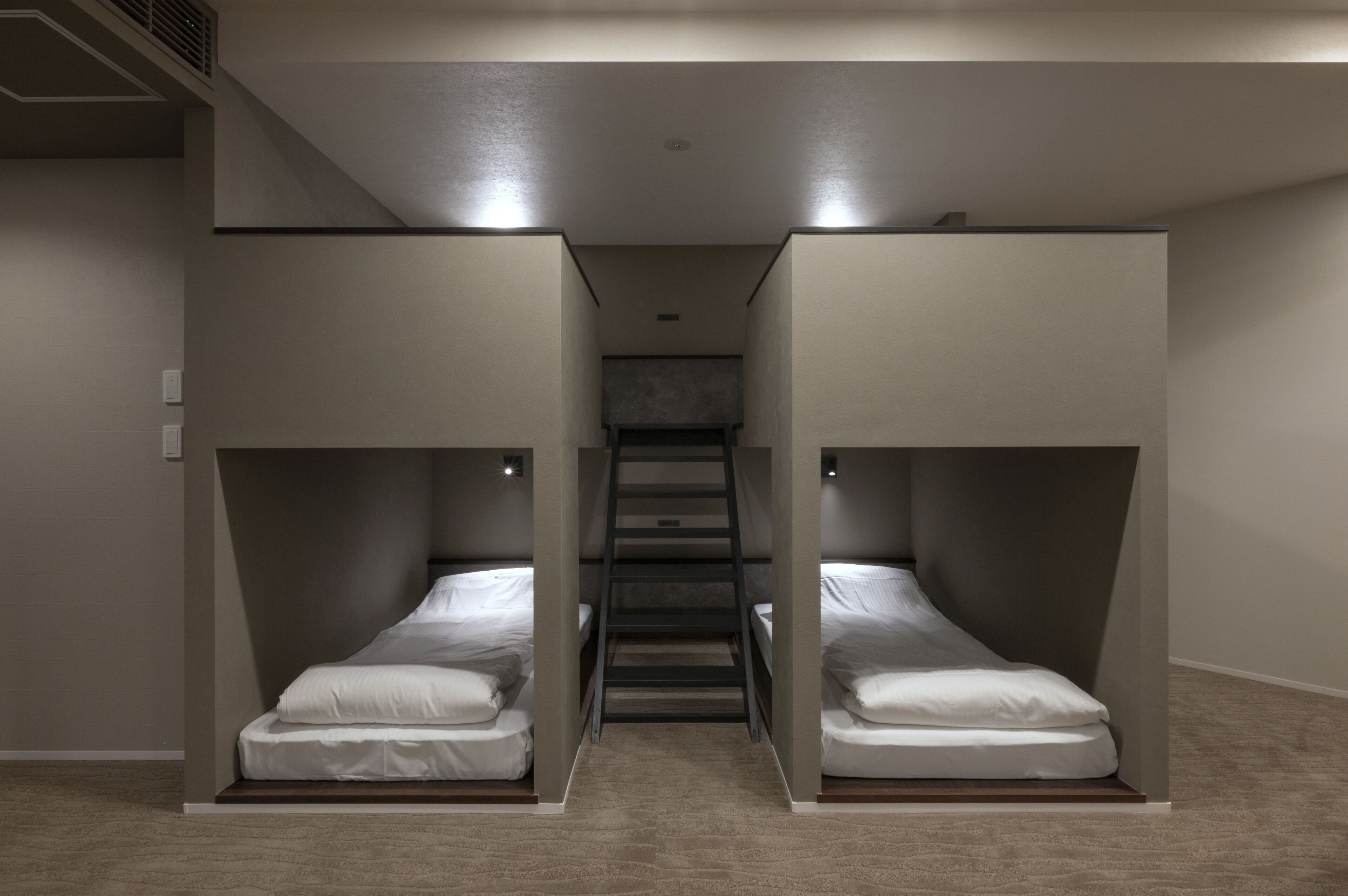 A room with two bunk beds, a staircase, and a carpeted floor.