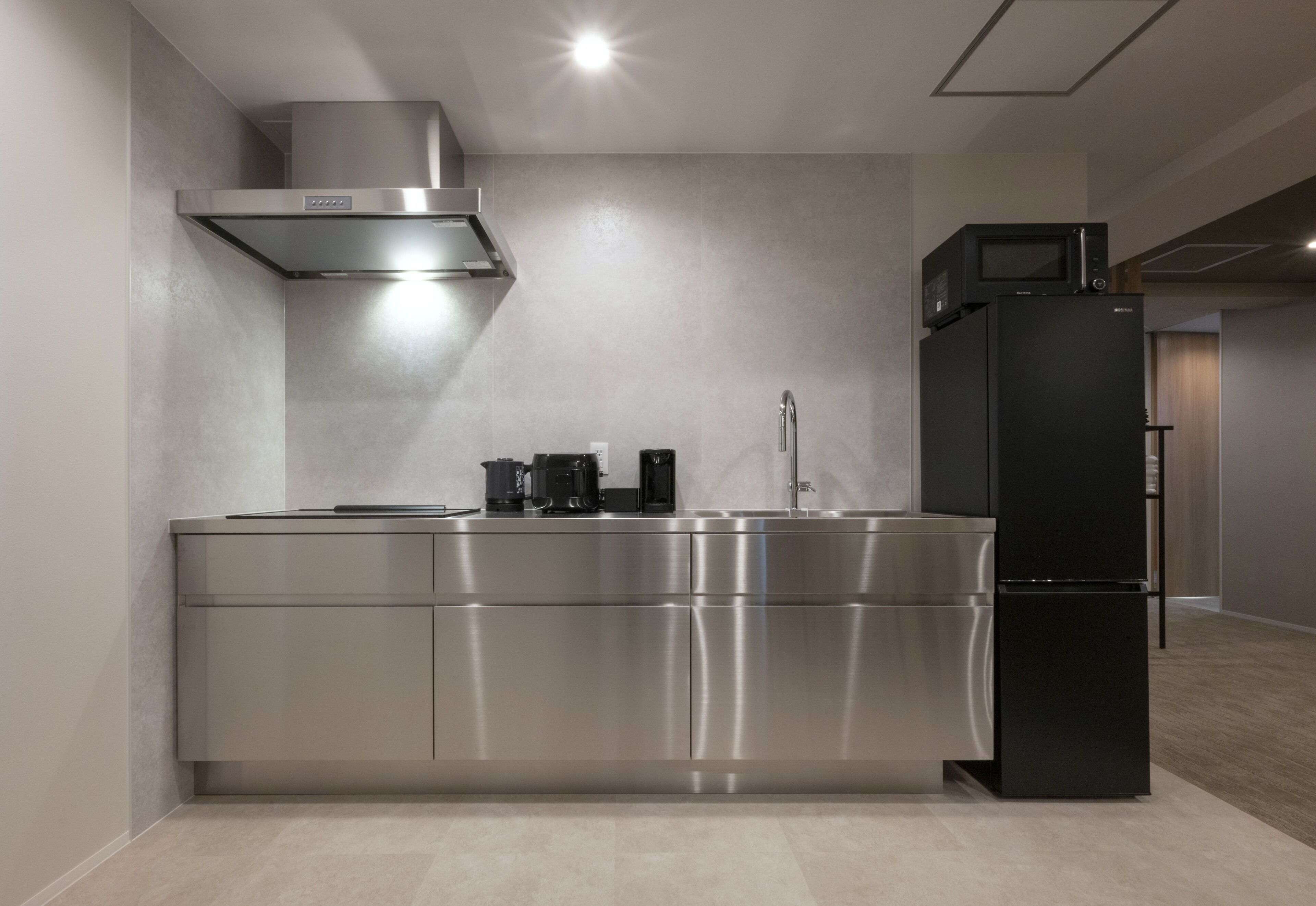 A modern kitchen with stainless steel appliances, a built-in oven, and a microwave on top of a refrigerator.