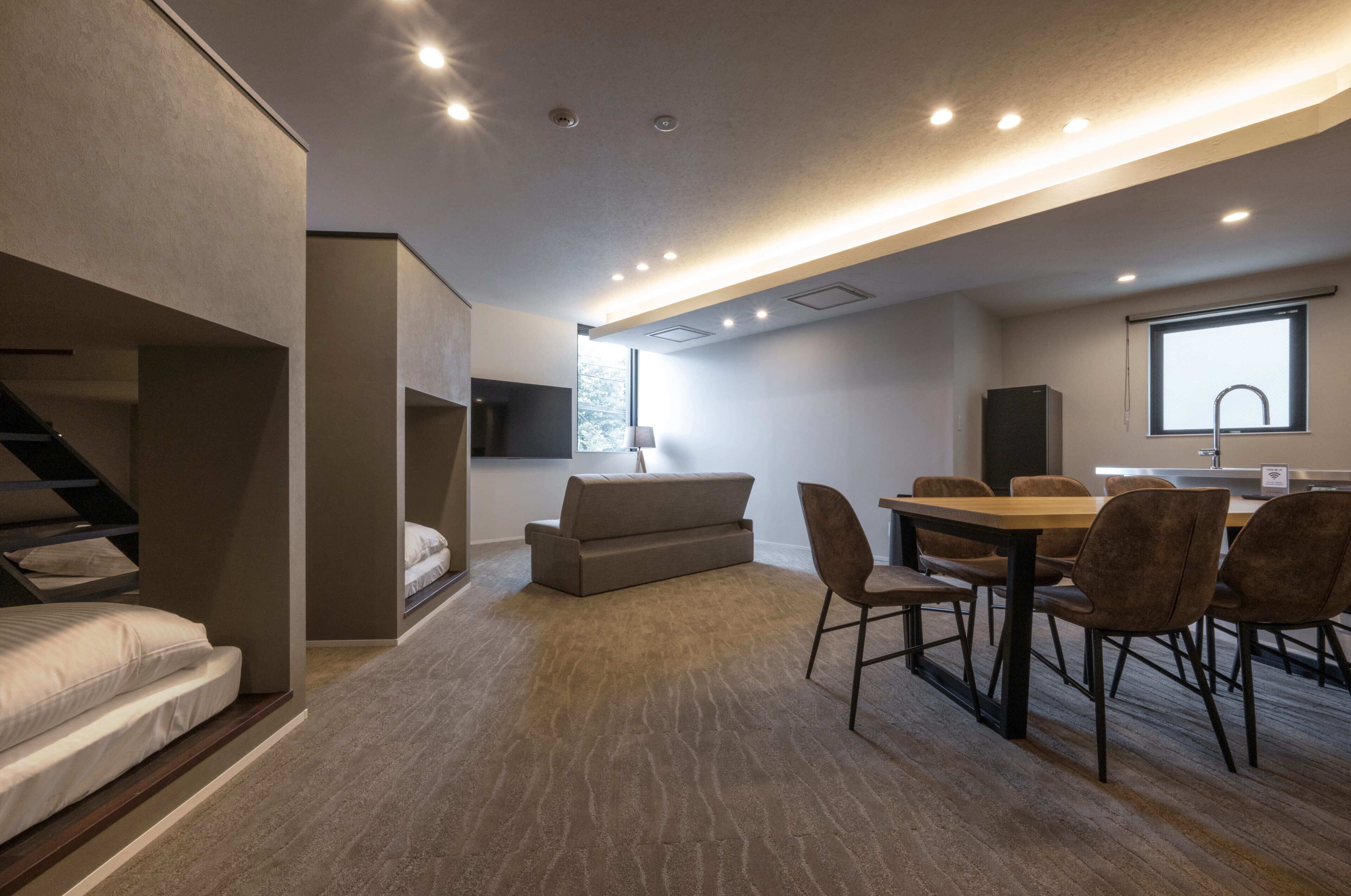 A modern interior with a sofa, dining table, chairs, a kitchen area, and a staircase.