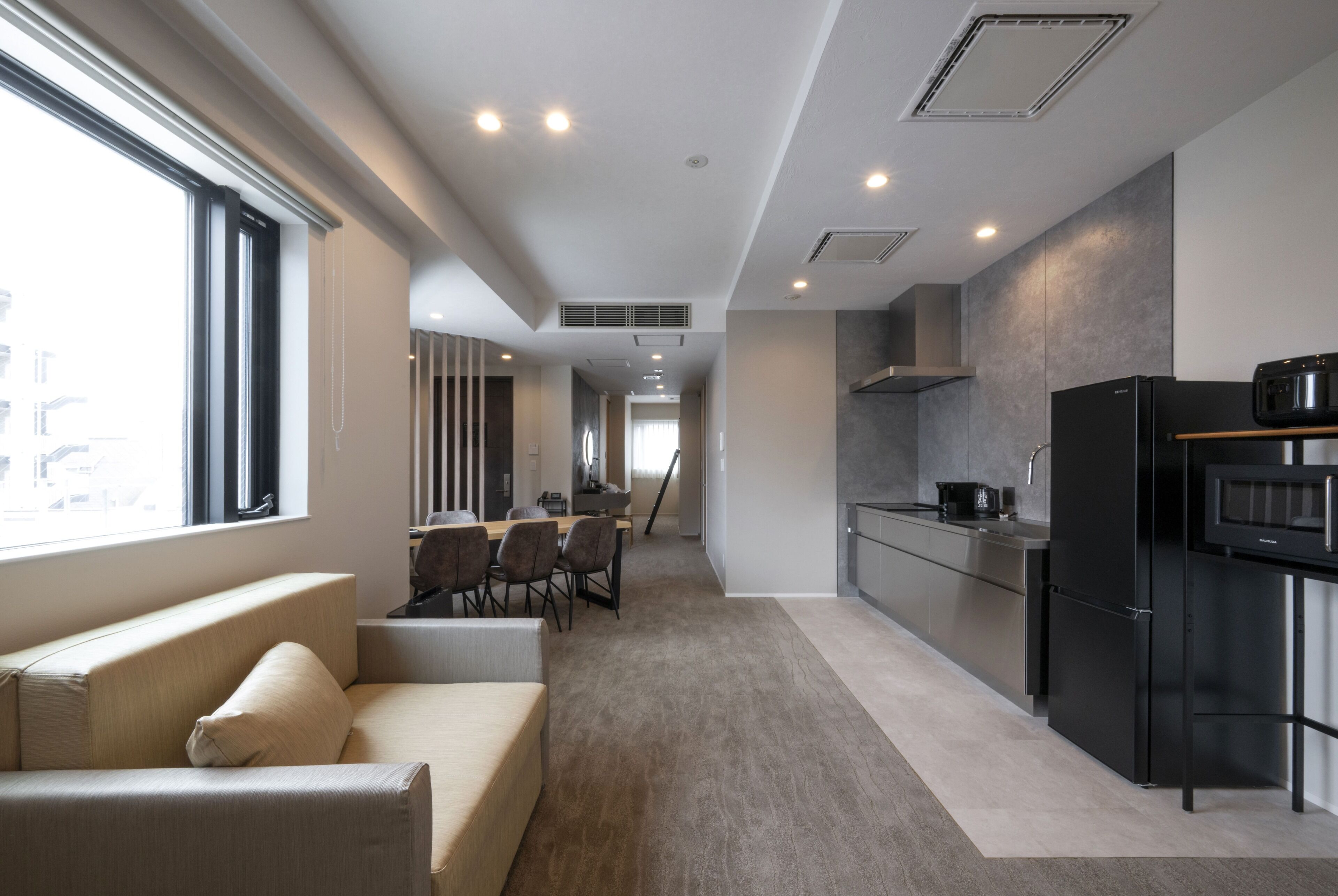 A modern kitchen with a refrigerator, microwave, and dining area with chairs and a table.