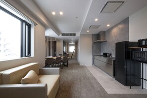 Una cocina moderna con refrigerador, microondas y comedor con sillas y mesa.