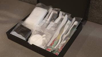 A black box containing a cotton set, a toothbrush, a tube of toothpaste, and a toothbrush head.