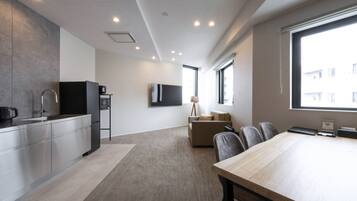 Una cocina moderna con electrodomésticos de acero inoxidable, una zona de comedor con mesa de madera y un rincón de descanso con sofá.