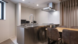 Una cucina moderna con isola centrale, elettrodomestici in acciaio inossidabile e zona pranzo con tavolo e sedie in legno.