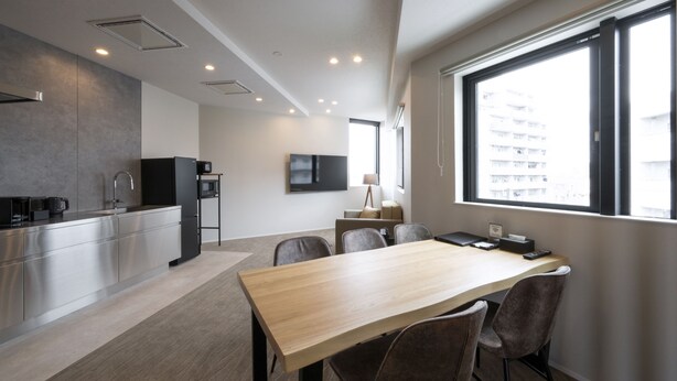 Una cucina moderna con elettrodomestici in acciaio inossidabile, una zona pranzo con tavolo e sedie in legno, e un'ampia finestra con vista sulla città.