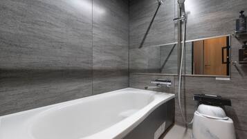 Un baño moderno con una bañera grande, una ducha y un espejo.
