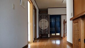 A hallway with wooden flooring, a blue mat, a wooden door, and a traditional Japanese sliding door. - Usa Usa no Petit Farm (Omachi)