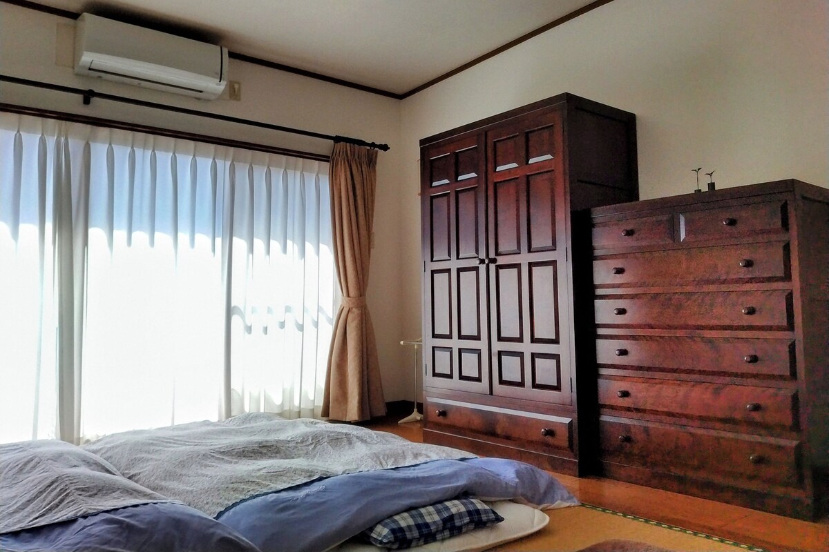 Un dormitorio con cama, armario y ventana con cortinas.