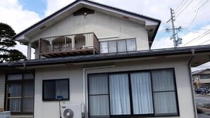 A two-story building with a balcony on the upper floor, large windows, and an air conditioning unit on the ground floor. - Usa Usa no Petit Farm (Omachi)