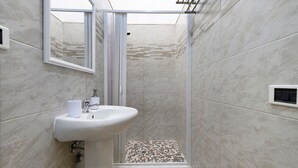 A bathroom with a shower, a sink, and a mirror.