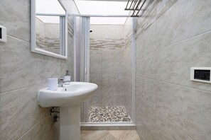 Un baño con ducha, lavamanos y espejo.