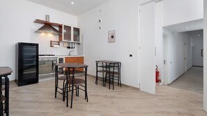 A modern kitchen with a refrigerator, oven, and dining area with chairs and tables.