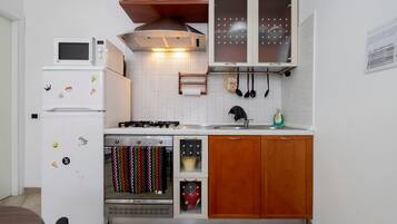 Une cuisine compacte équipée d’un réfrigérateur, d’un four à micro-ondes, d’une cuisinière, d’un four et de meubles de rangement en bois.
