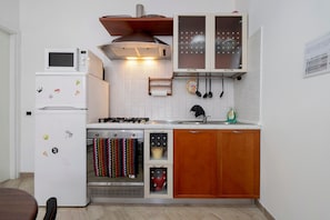 Cocina compacta con refrigerador, microondas, estufa, horno y armarios de madera.