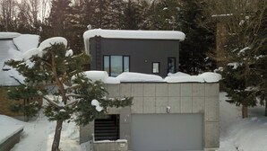 A modern building with a garage door, surrounded by snow-covered trees.