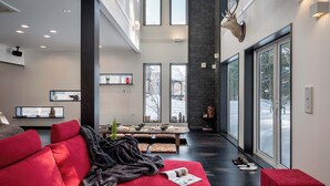 A modern living room with a red sofa, a fireplace, and large windows.