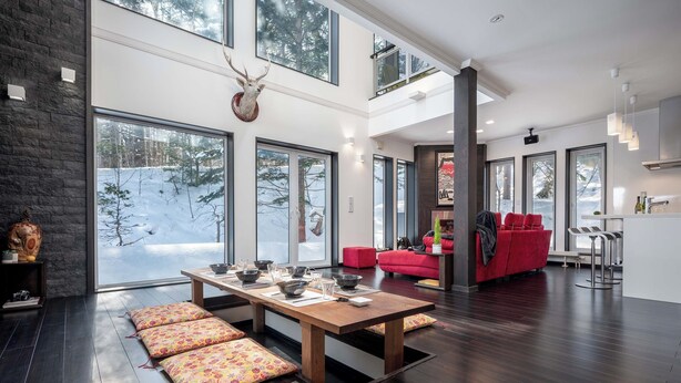 A modern interior with a dining area, red seating, and large windows.