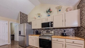 A kitchen with white cabinets, a stainless steel refrigerator, a microwave, an oven, and a coffee maker. - 3BR Atlanta Airport Home | Pet Friendly + Parking (Union City)