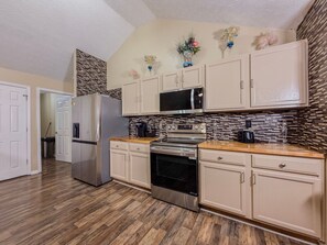 A kitchen with white cabinets, a stainless steel refrigerator, a microwave, an oven, and a coffee maker. - 3BR Atlanta Airport Home | Pet Friendly + Parking (Union City)