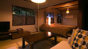 A room with a bed, a sofa, a television, and a table.