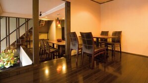 A dining area with a wooden table and chairs, a staircase, and a view into another room.