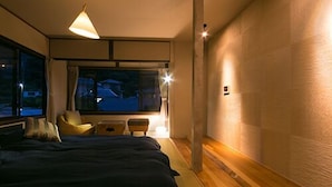 A bedroom with a bed, bedside tables, a window, and a wall-mounted light fixture.