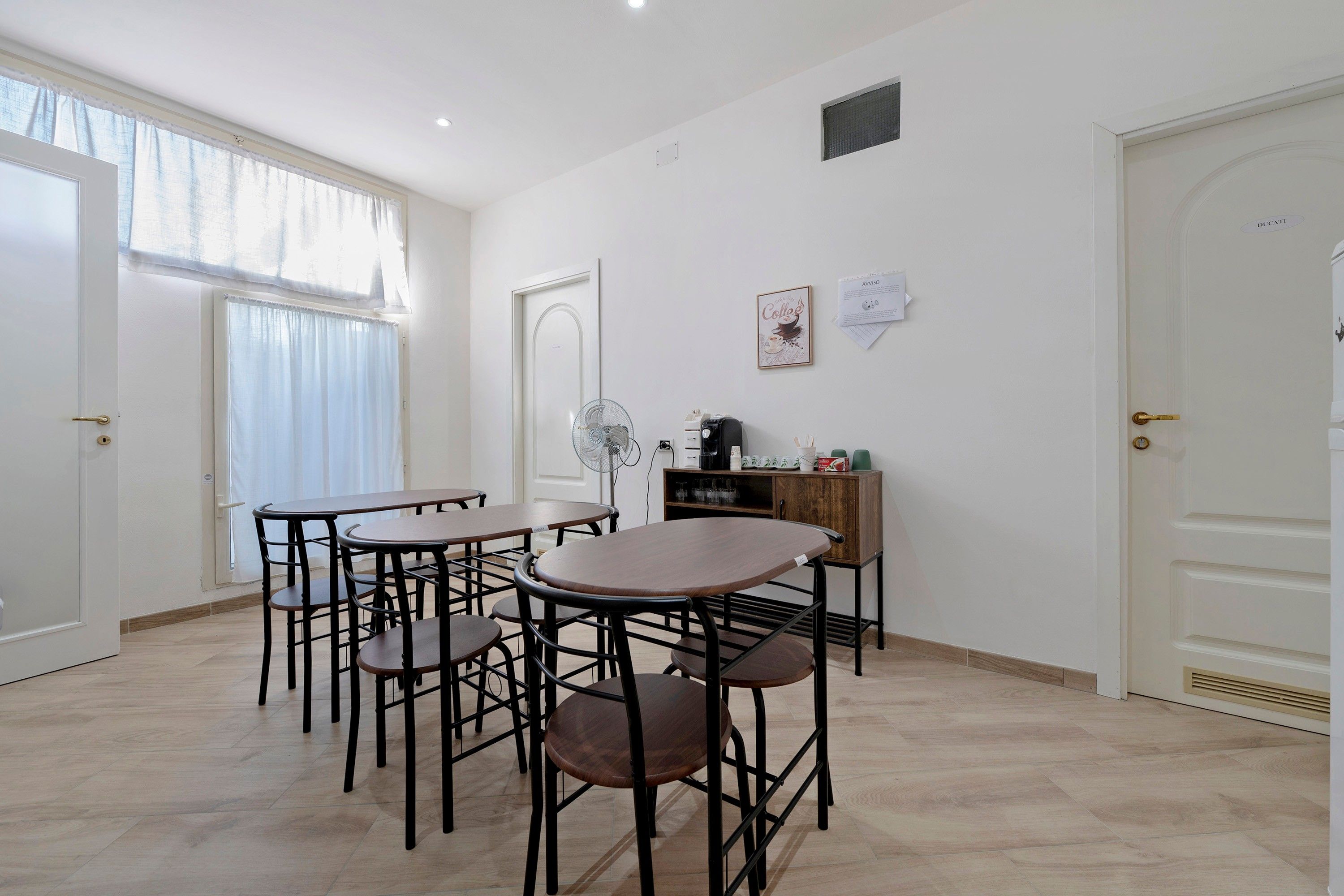 A dining area with a table and chairs, a fan, and a coffee machine.