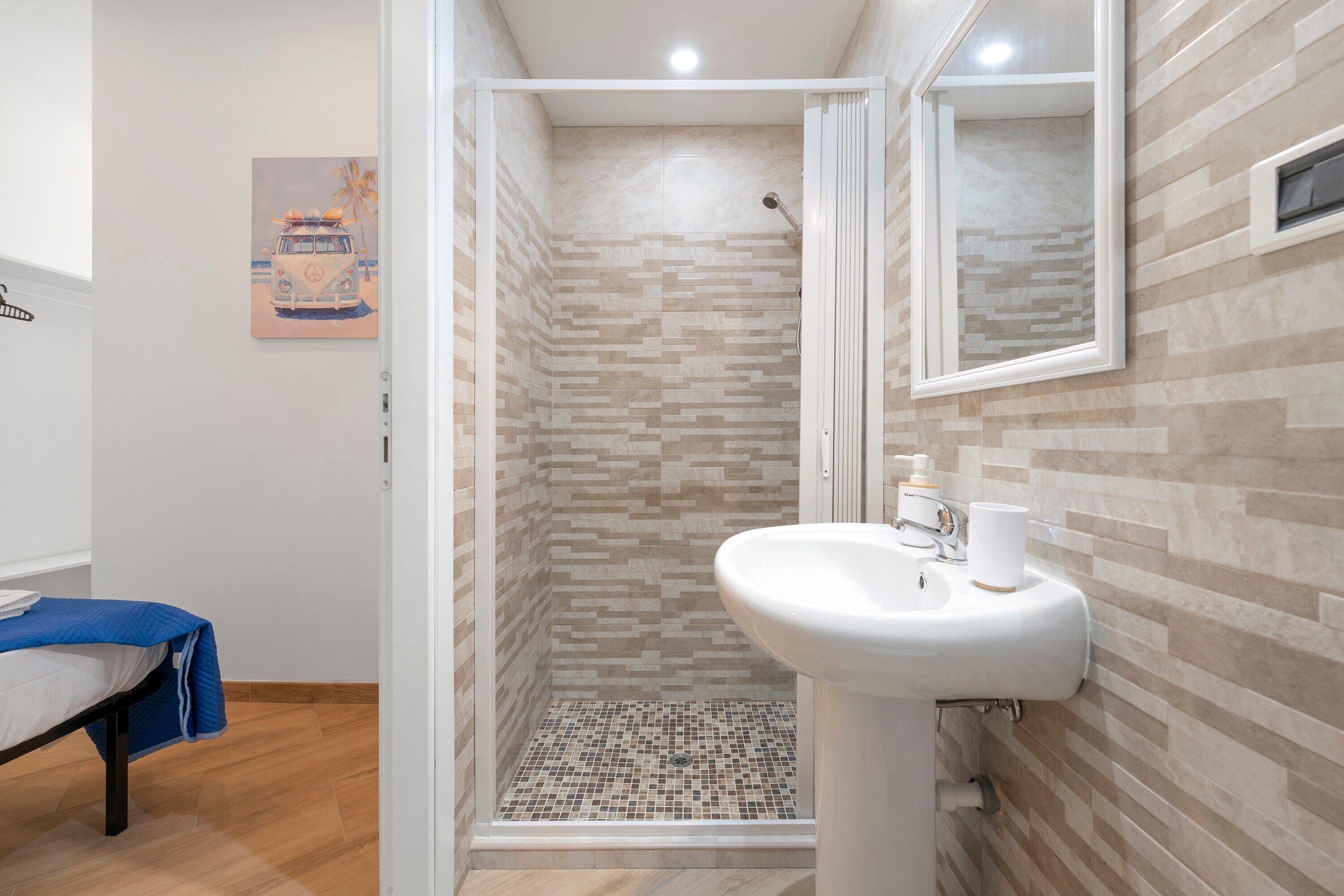 Une salle de bain avec une douche, un lavabo et un lit.