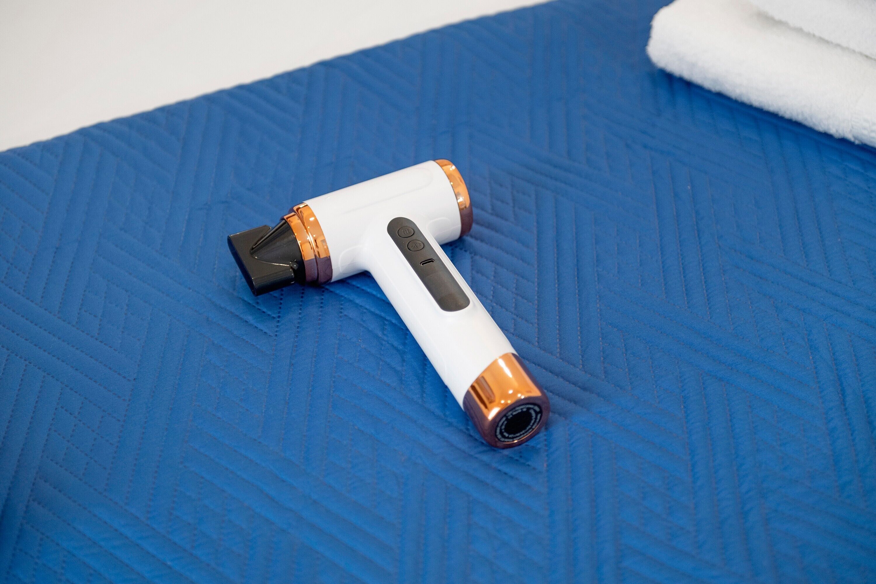 Un purificateur d’air portatif, de couleur blanche et orange, posé sur une surface bleue texturée.