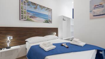 A hotel room with a bed, a bedside table, a nightstand, a wall-mounted artwork, and a wardrobe.